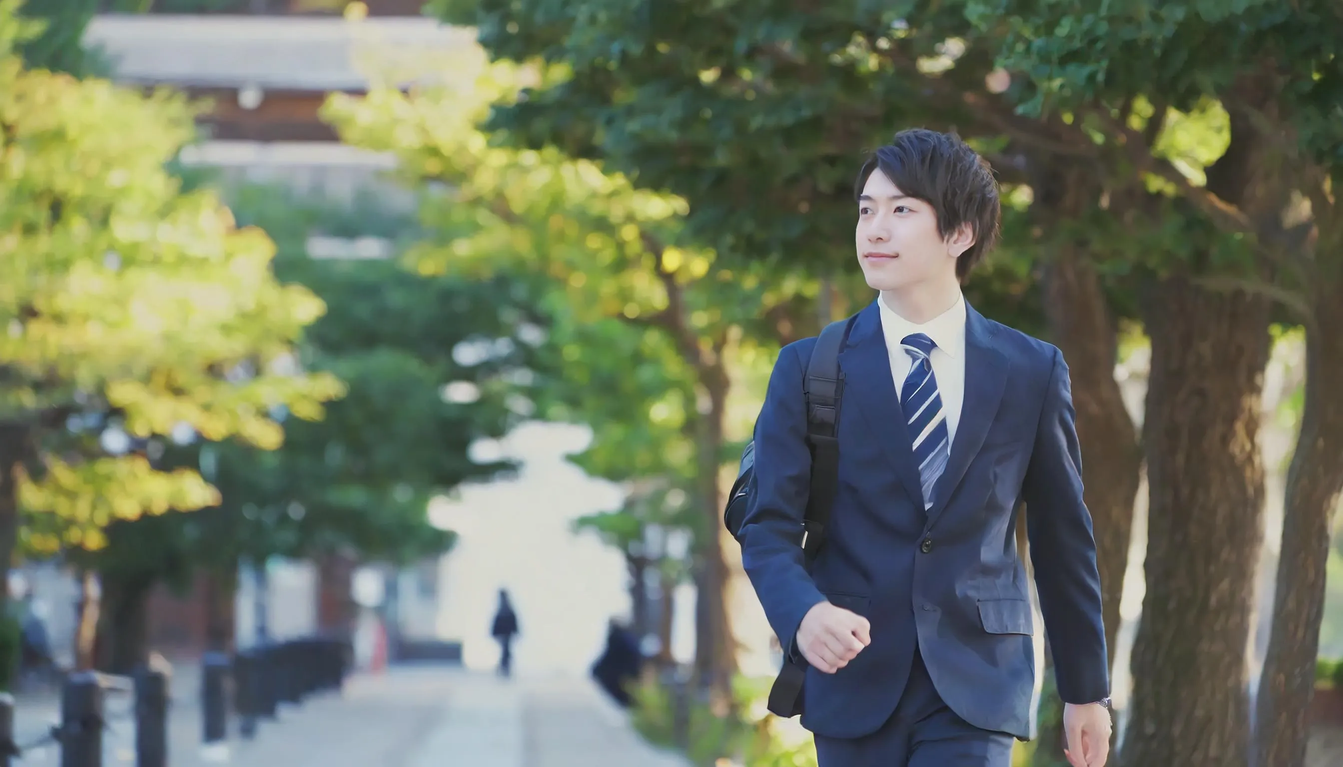 スーツを着て屋外を爽やかに歩く若い男性ビジネスパーソン
