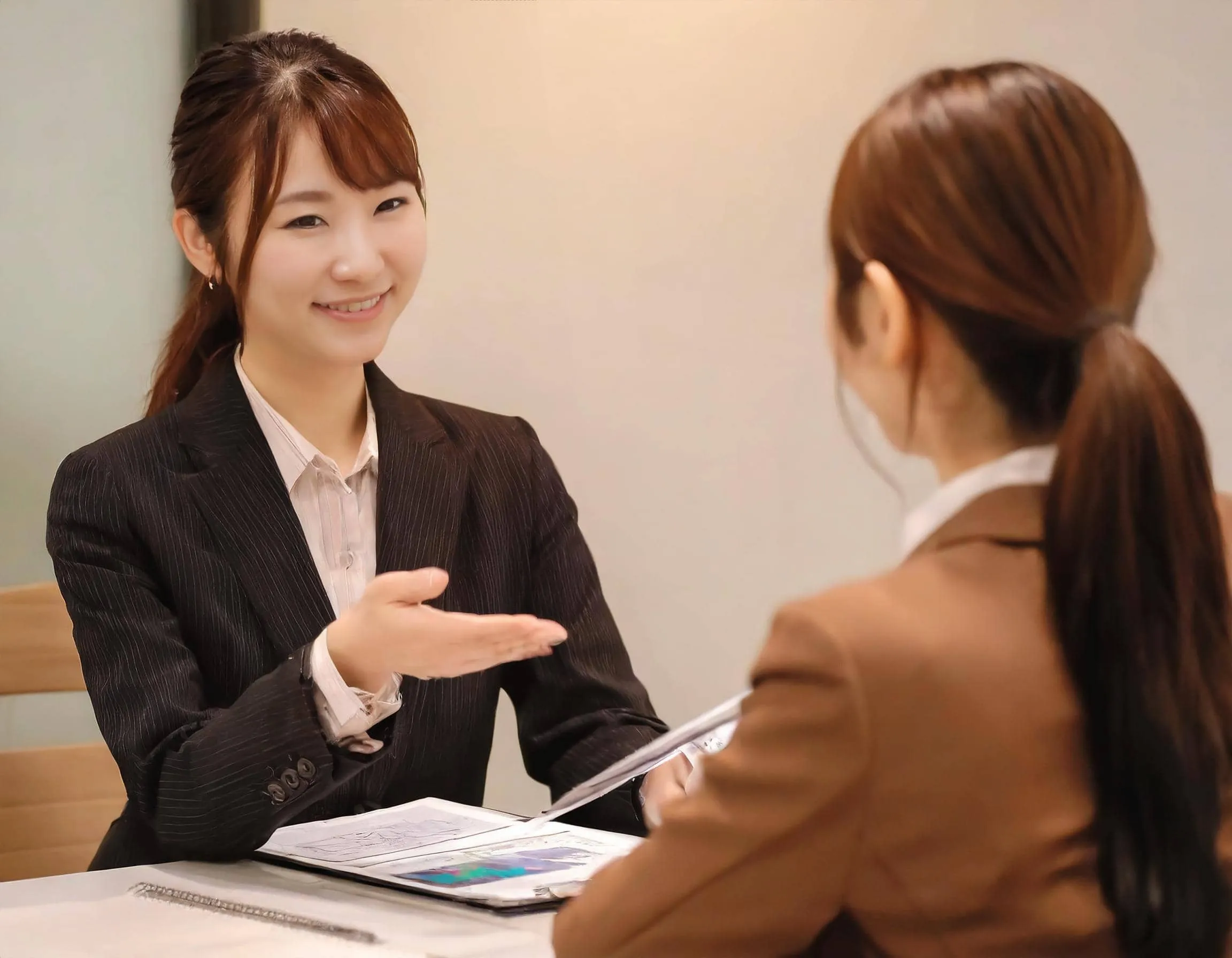 ノートPCを開いたカフェ風のオフィスで、笑顔で作業をする女性社員